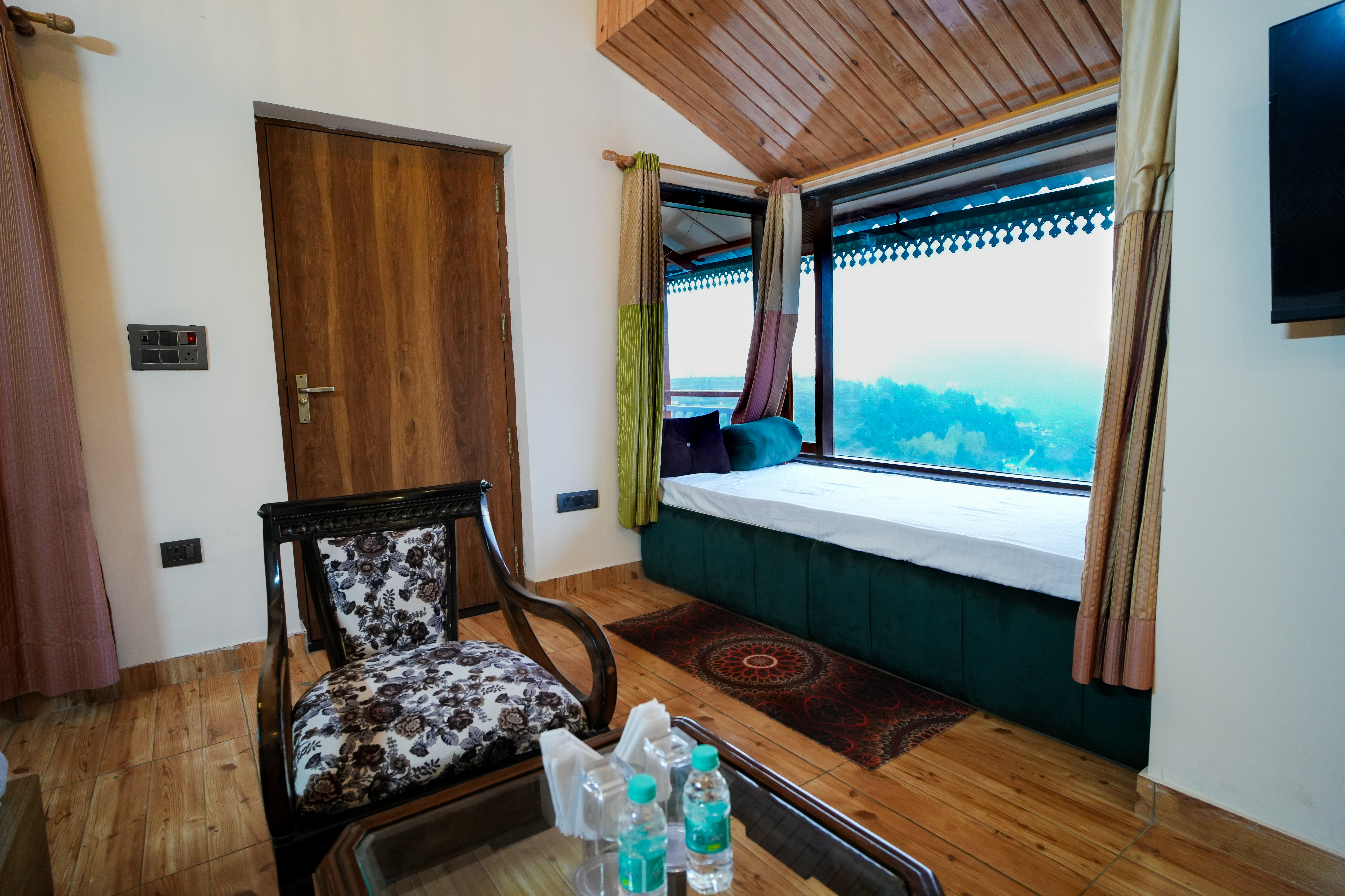 family-friendly bedroom with double bed and seating area at Monal Meadows villa in Naukuchiatal