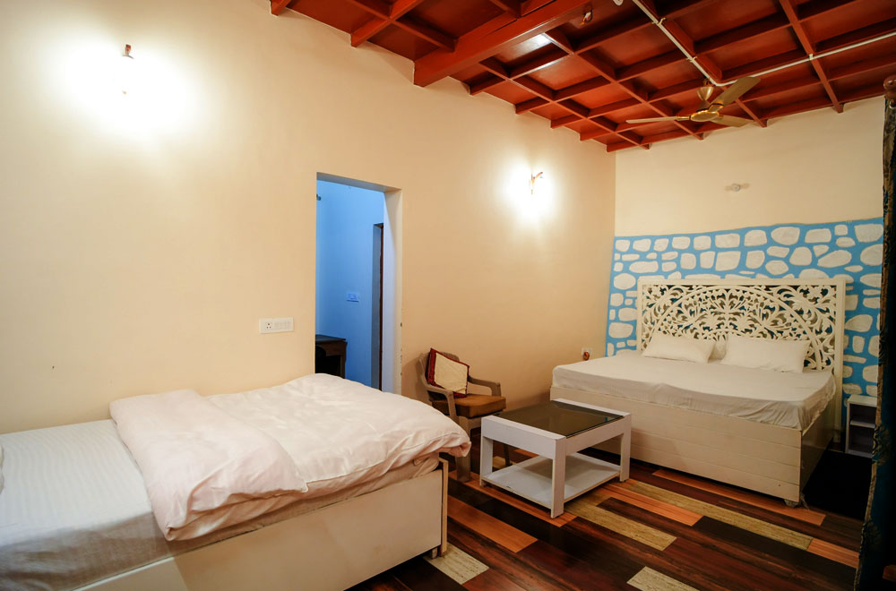 Spacious luxury bedroom at Monal Meadows homestay in Naukuchiatal with warm wooden interiors
